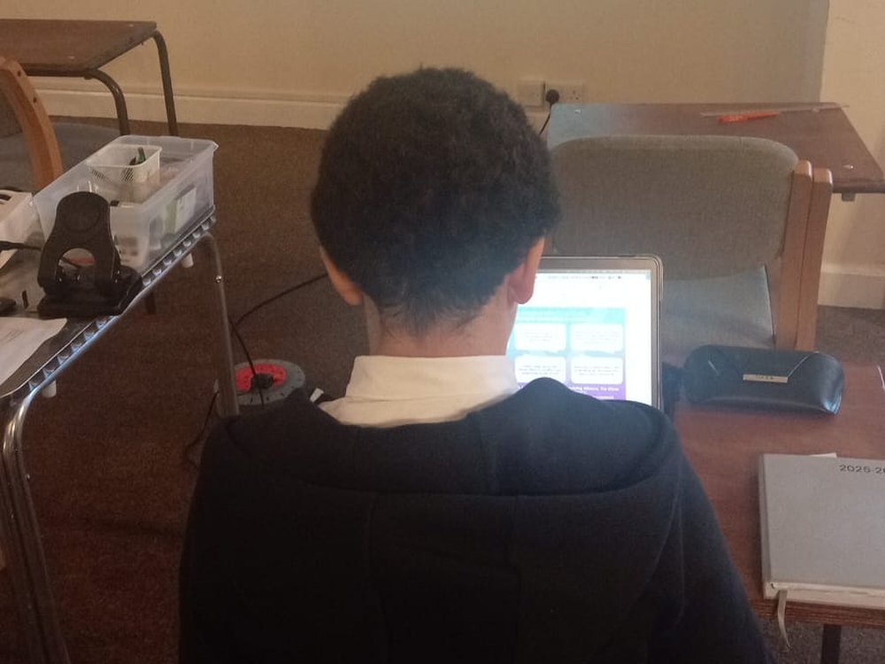 A student working at a laptop during a class discussion activity