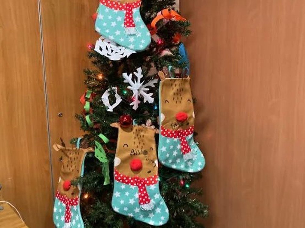 A Christmas tree hung with handmade reindeer stockings and paper snowflakes