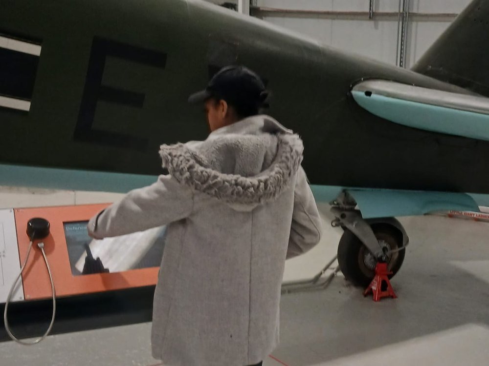 A student using an interactive display beside a preserved aircraft at the RAF museum