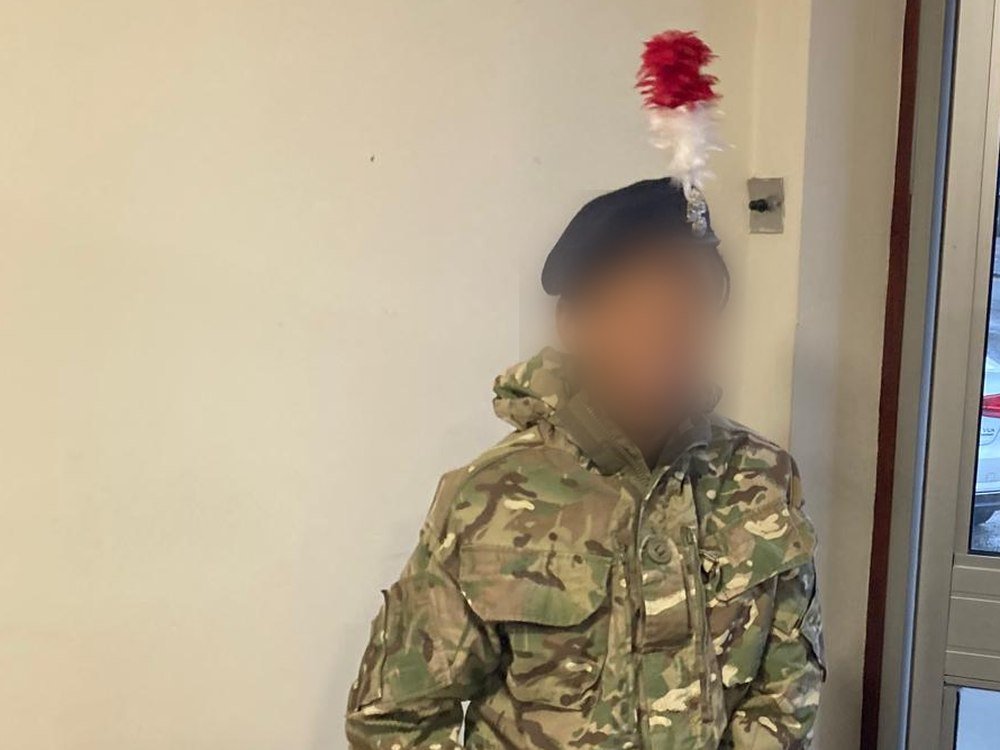 A student wearing an army cadet uniform and beret during a visit, faces obscured