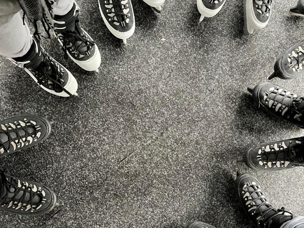 A group standing in a circle wearing ice skates, seen from above