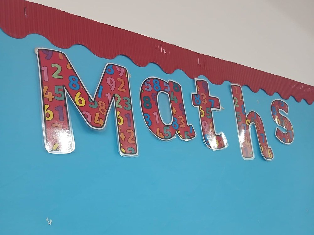 A Maths display board on a classroom wall, with the word Maths in colourful number-patterned letters