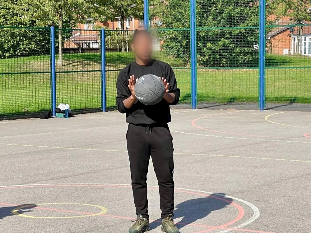 A student holding a basketball on the outdoor court