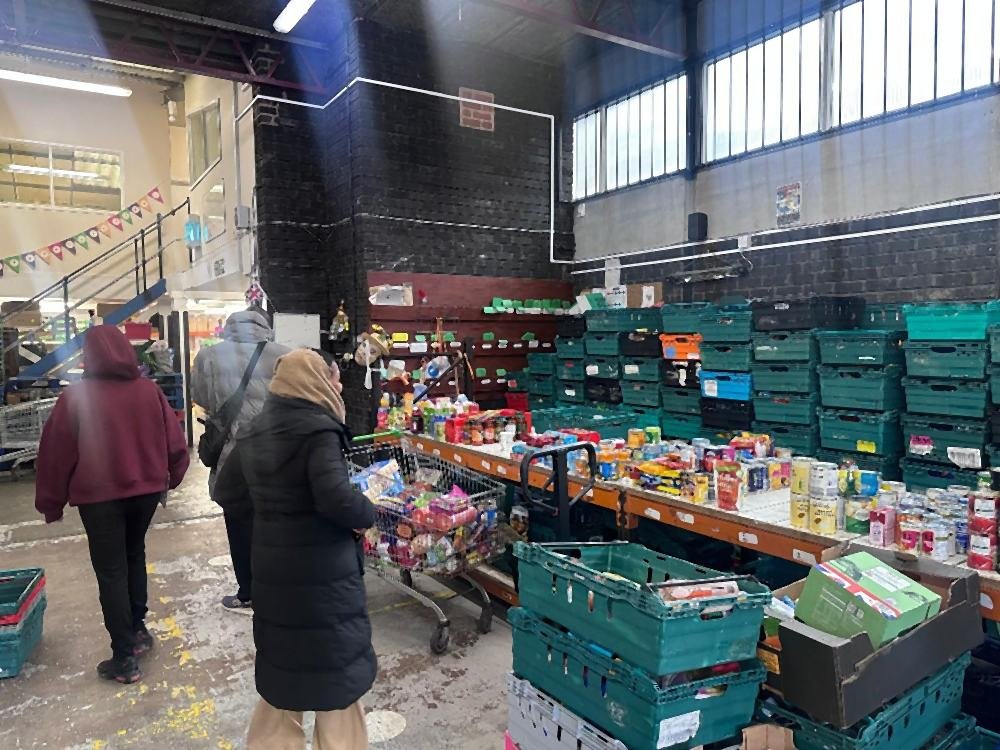 Students walking through the Black Country Foodbank warehouse, past tables and crates of donated food
