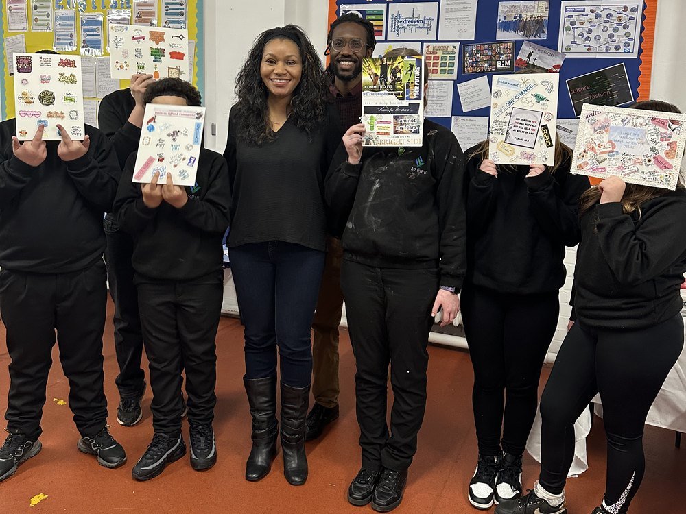 Students holding up vision boards they have made, with two visiting adults